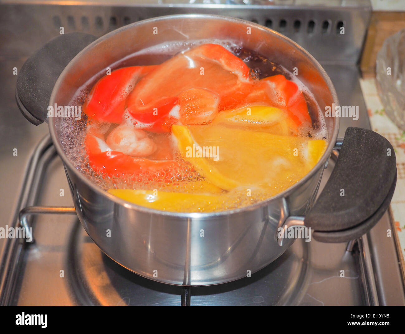 Gelbe und rote Paprika Gemüse gesunde vegetarische Küche Essen in einem Saucepot auf Gasherd Stockfoto