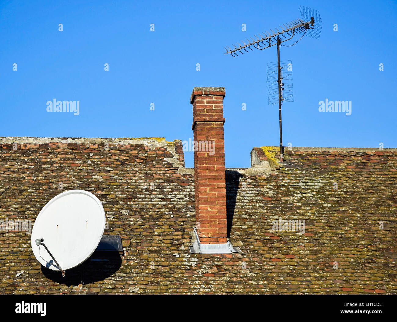 Sat-Schüssel und TV Antenne auf dem Dach eines alten Gebäudes Stockfoto
