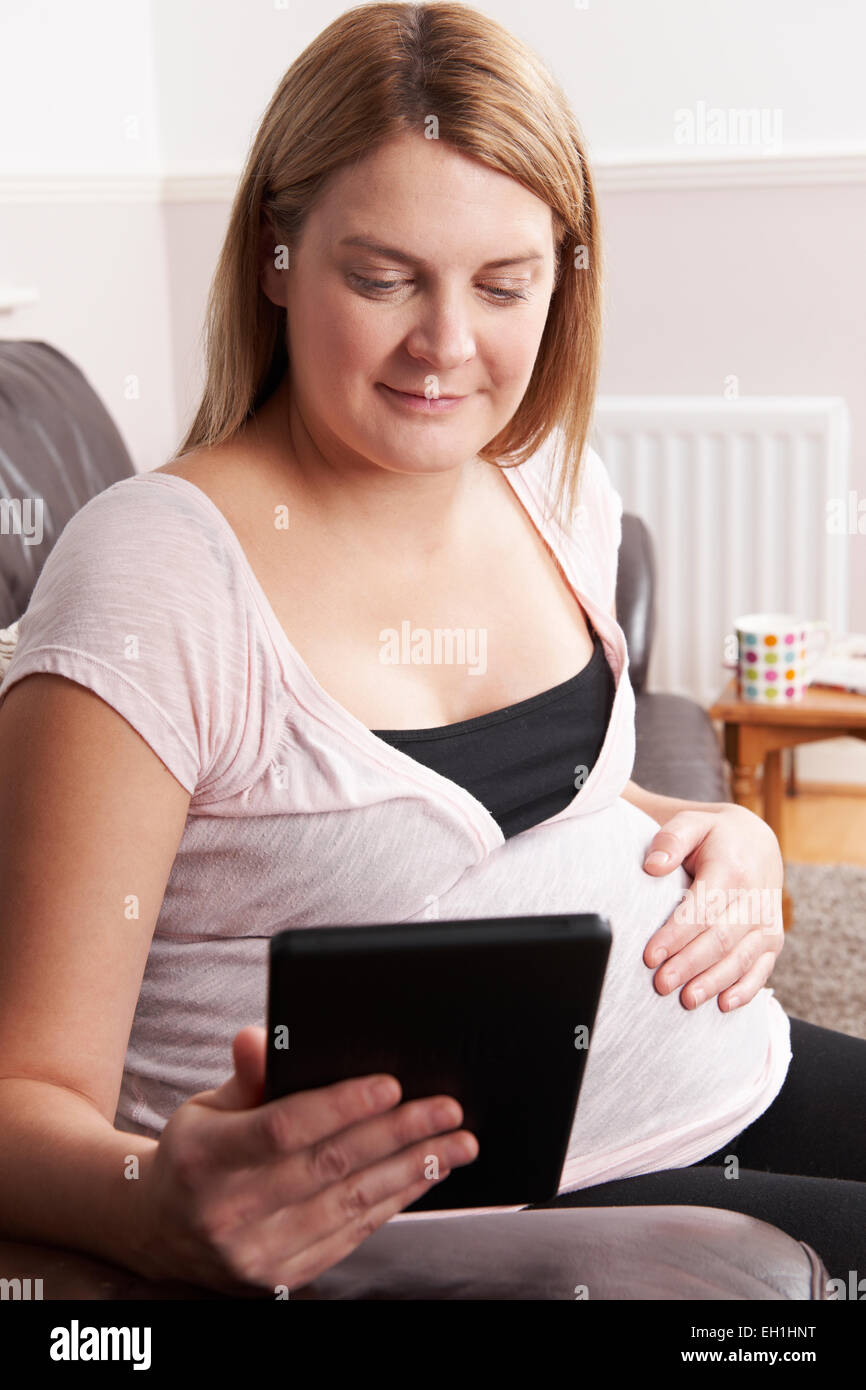 Schwangere Frau, die mit E-Reader zu Hause entspannen Stockfoto
