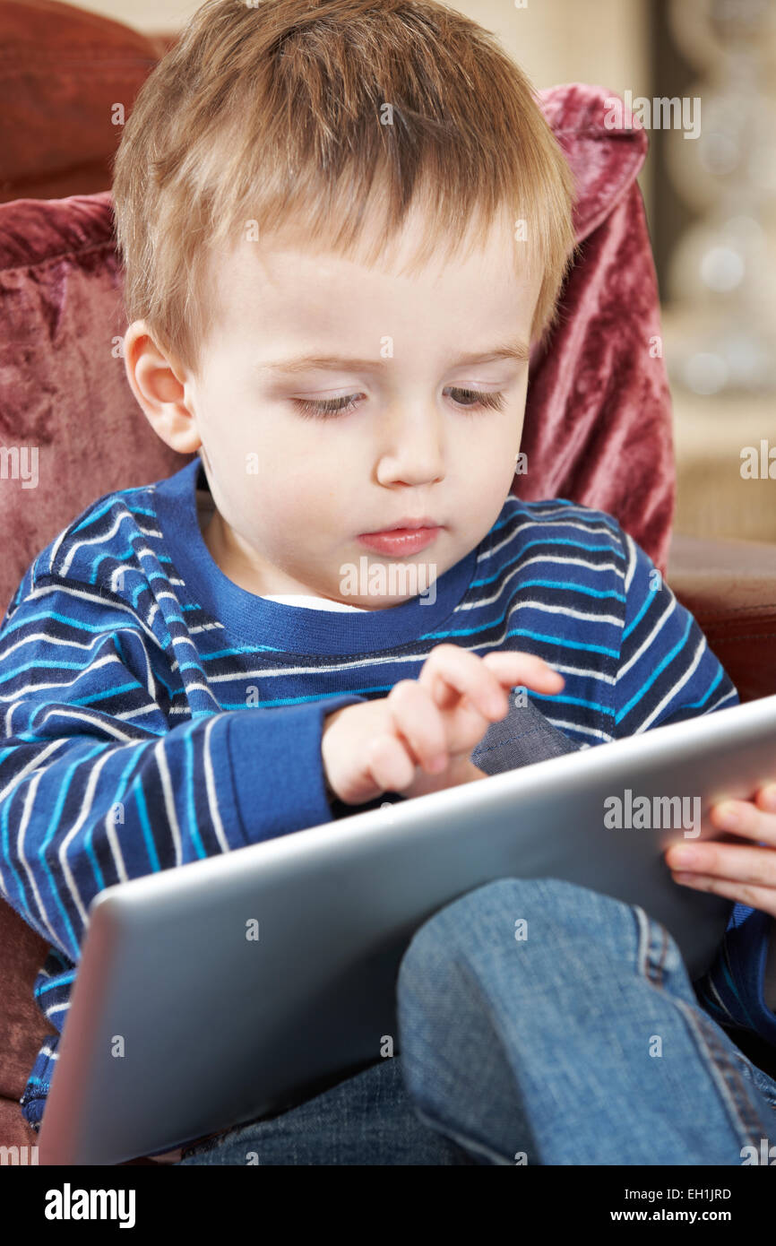 Junge sitzt auf dem Sofa und spielt mit Digital-Tablette Stockfoto
