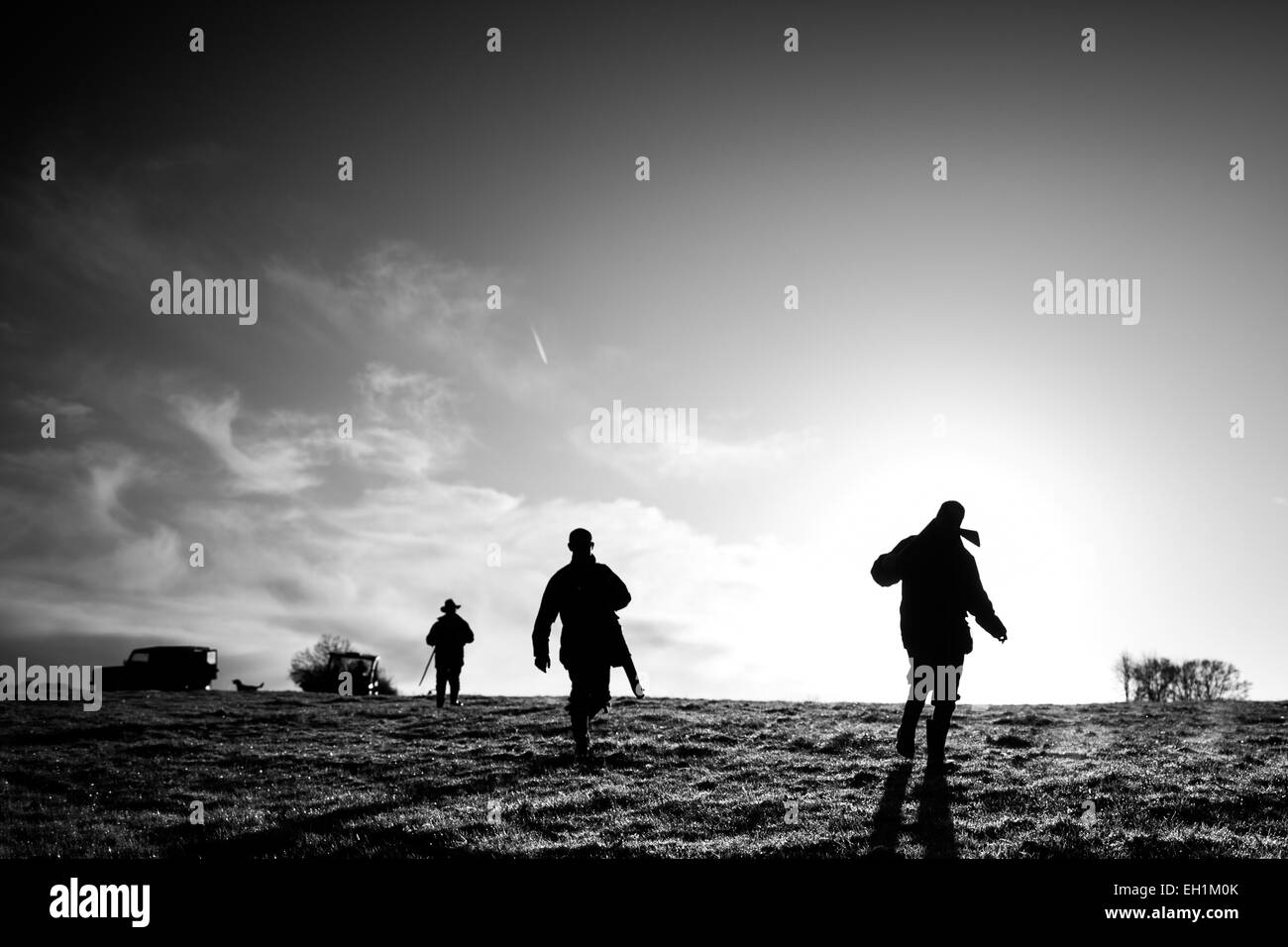 Schwarz / weiß Landschaft Foto der drei männliche Waffen zu Fuß auf das nächste Laufwerk auf ein Spiel zu schießen in England, UK Stockfoto