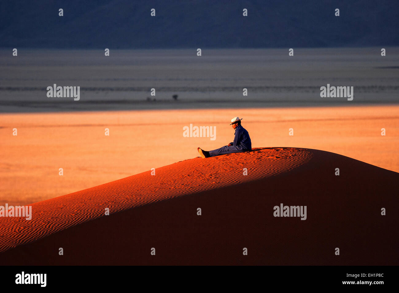 Lokale Mann sitzt auf einer Sanddüne, genießen das Abendlicht südlichen Ausläufer der Namib-Wüste, Namibia Stockfoto