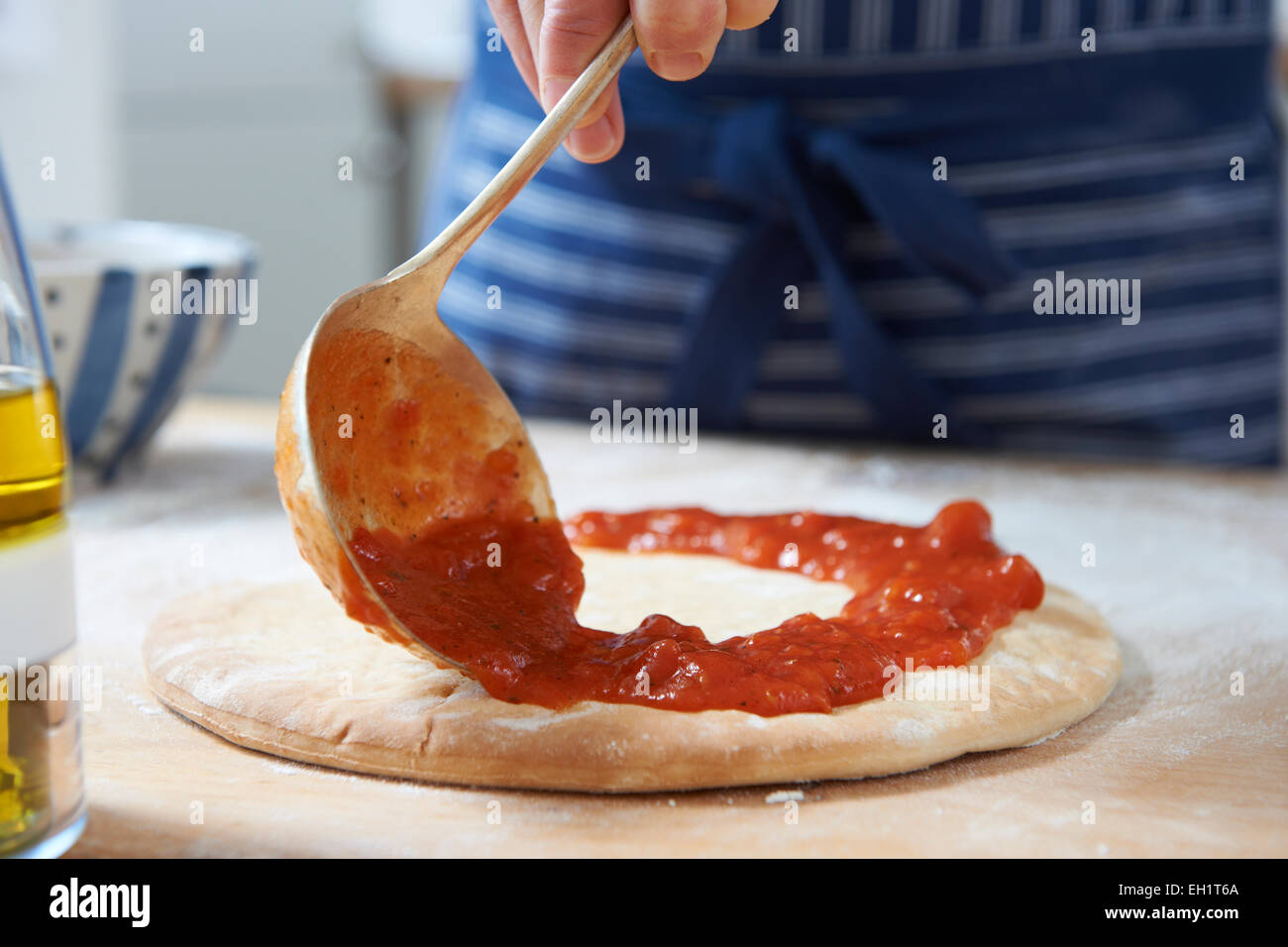 Nahaufnahme von Pizzateig Tomatensauce hinzufügen Stockfoto