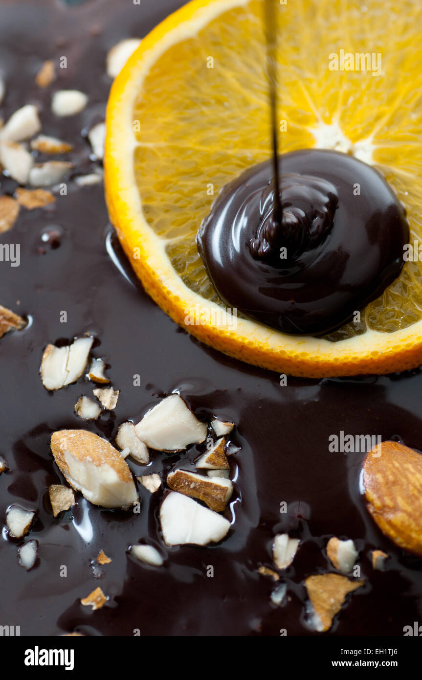 Gehackte Mandeln und eine Orangenscheibe in geschmolzene Schokolade. Stockfoto