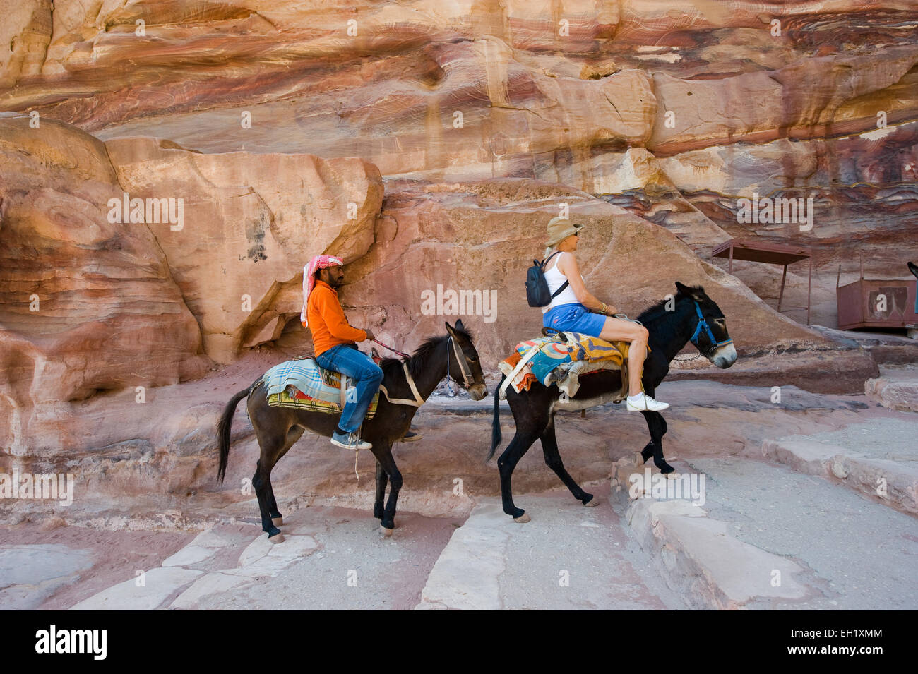 PETRA, Jordanien - 12. Oktober 2014: Zwei Esel mit seinem Besitzer und ein Tourist sind die lange Treppe hinauf zu den 'Ad Deir' Monaste Klettern Stockfoto