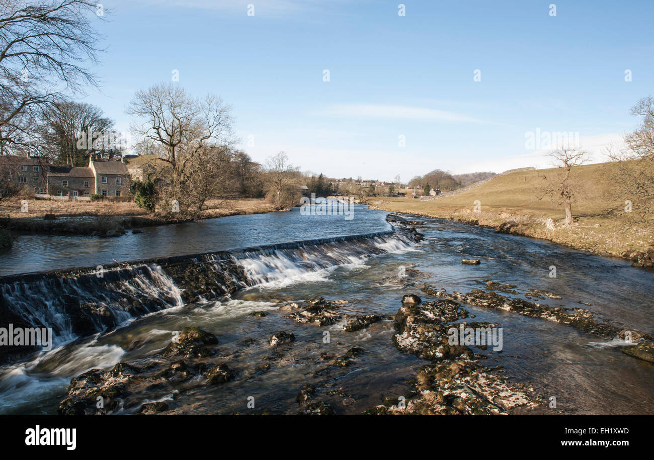 Fluss einen kleinen Wasserfall in einer englischen ländlichen Landschaft Landschaft Szene mit Bauernhaus Stockfoto