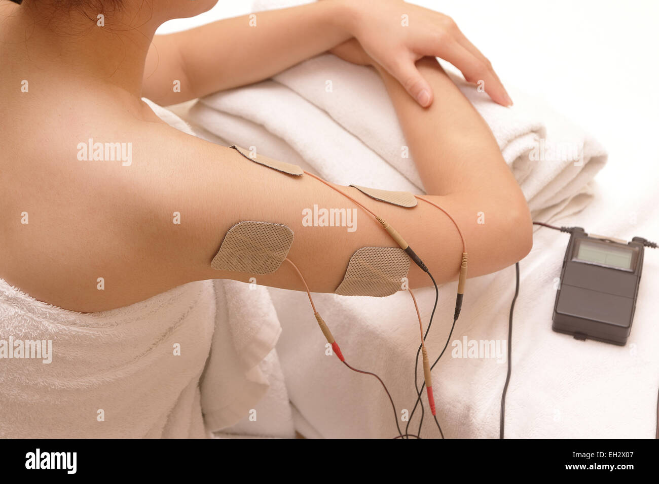 Asiatische Frau tut Massage der Elektro - Stimulation (TENs) für die Schulter Stockfoto