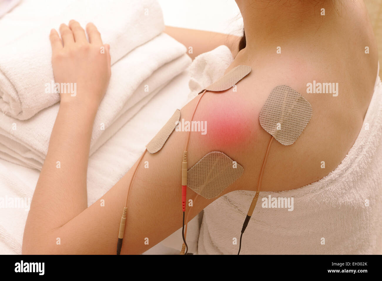 Asiatische Frau tut Massage der Elektro - Stimulation (TENs) für die Schulter Stockfoto