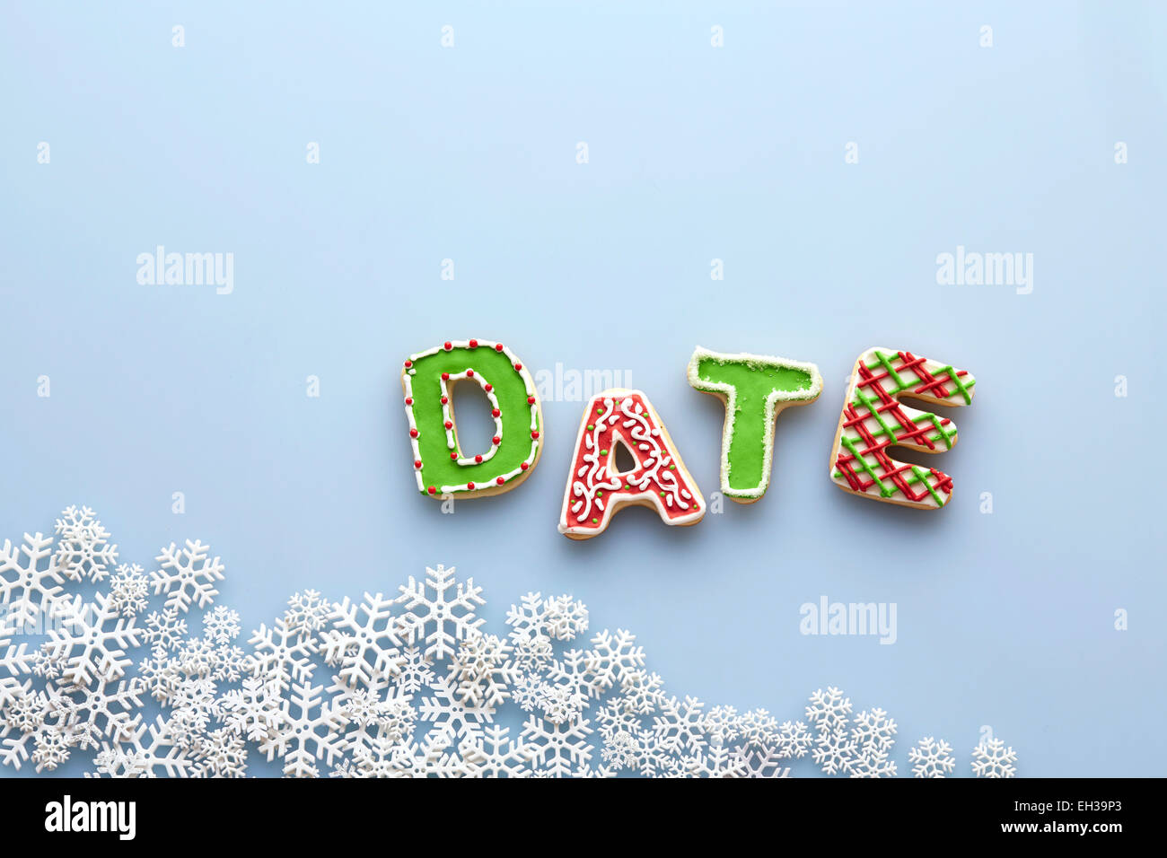 Obenliegende Ansicht von Brief Cookies Rechtschreibung Datum auf blauem Hintergrund mit Schneeflocken Stockfoto