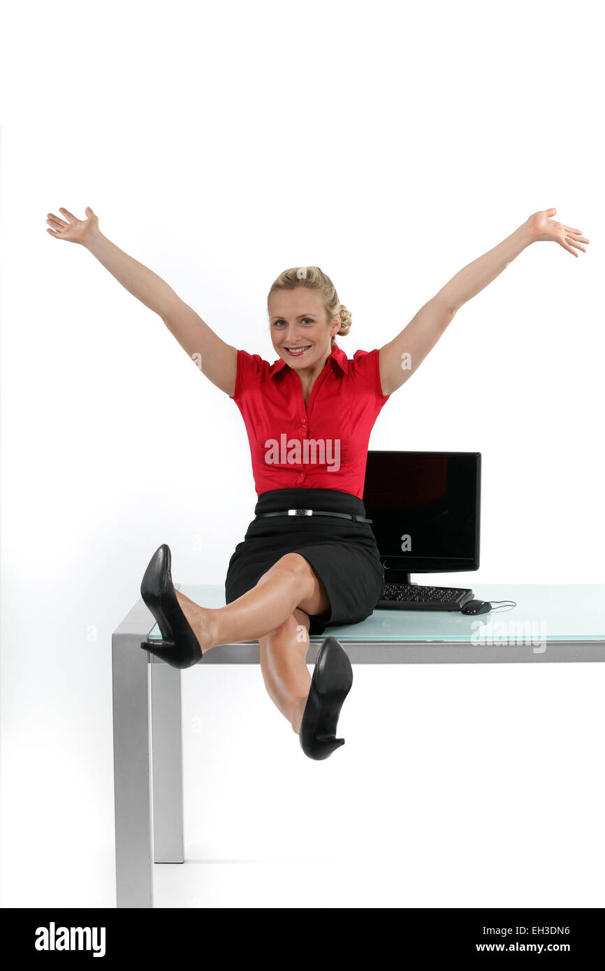 Entspannte Frau sitzt auf ihrem Schreibtisch Stockfoto