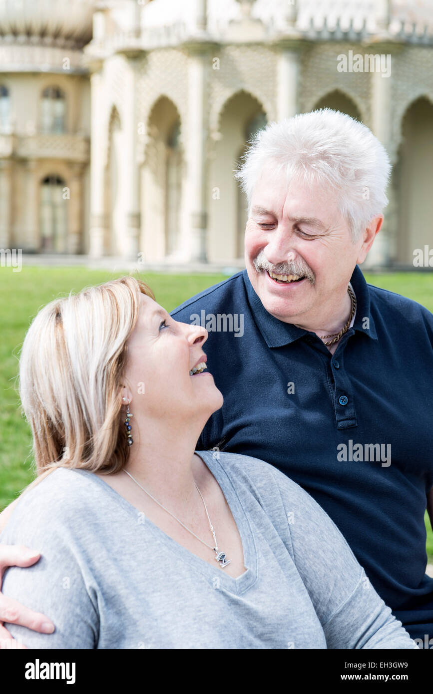 ein älteres Ehepaar kuscheln und Umarmung zeigt Liebe vor Brightons touristischen Wahrzeichen der Royal Pavilion auf dem Rasen Stockfoto