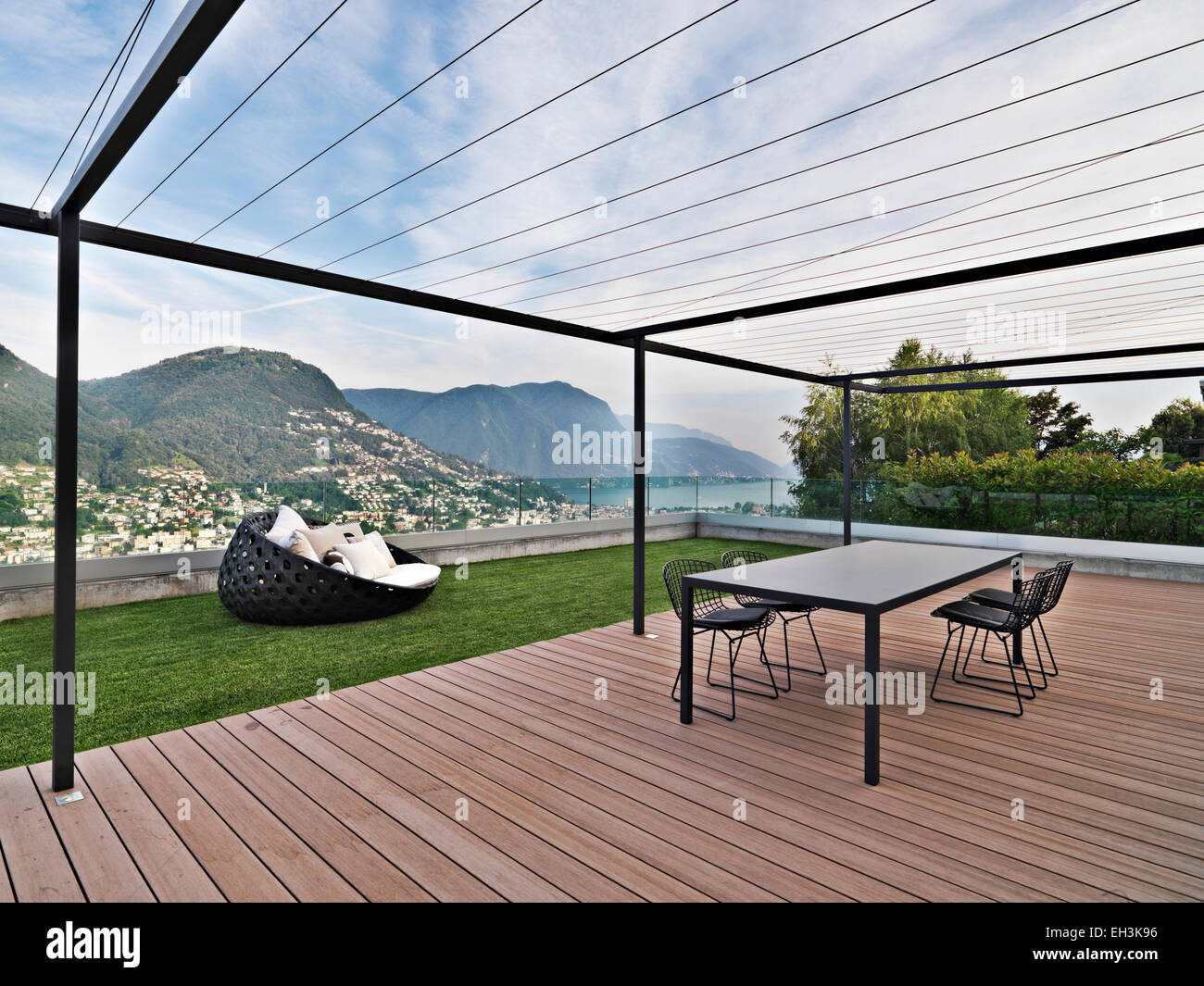 Außenansicht einer modernen Terrasse mit Esstisch mit Blick auf den See von Lugano, Schweiz Stockfoto