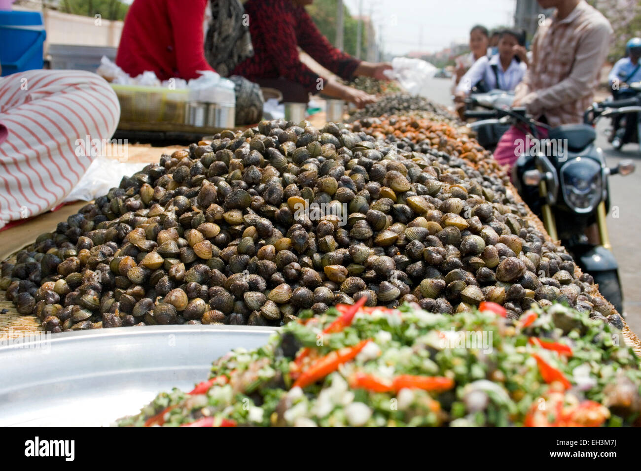 Ein Mann kauft von einem Speiselokal Händler in Kampong Cham, Kambodscha Schnecken in einer Garküche. Stockfoto