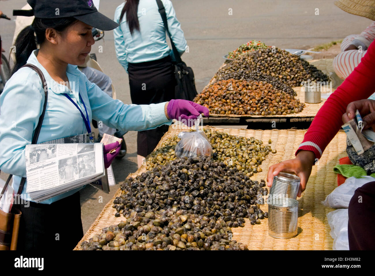 Eine Studentin kauft von einem Speiselokal Händler in Kampong Cham, Kambodscha Schnecken in einer Garküche. Stockfoto