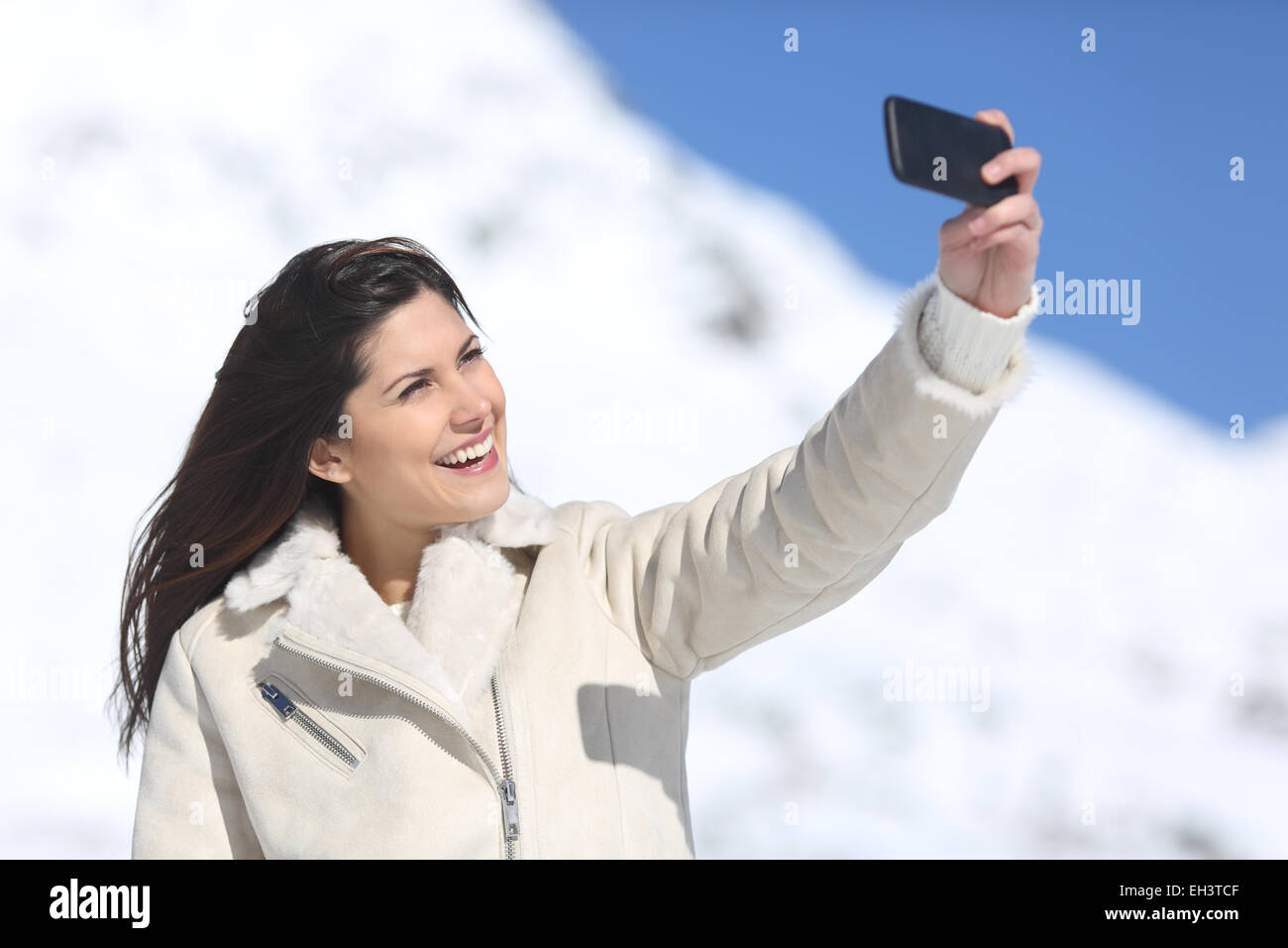 Mode Frau Fotografieren ein Selbstporträt im Winterurlaub mit einem schneebedeckten Berg im Hintergrund Stockfoto
