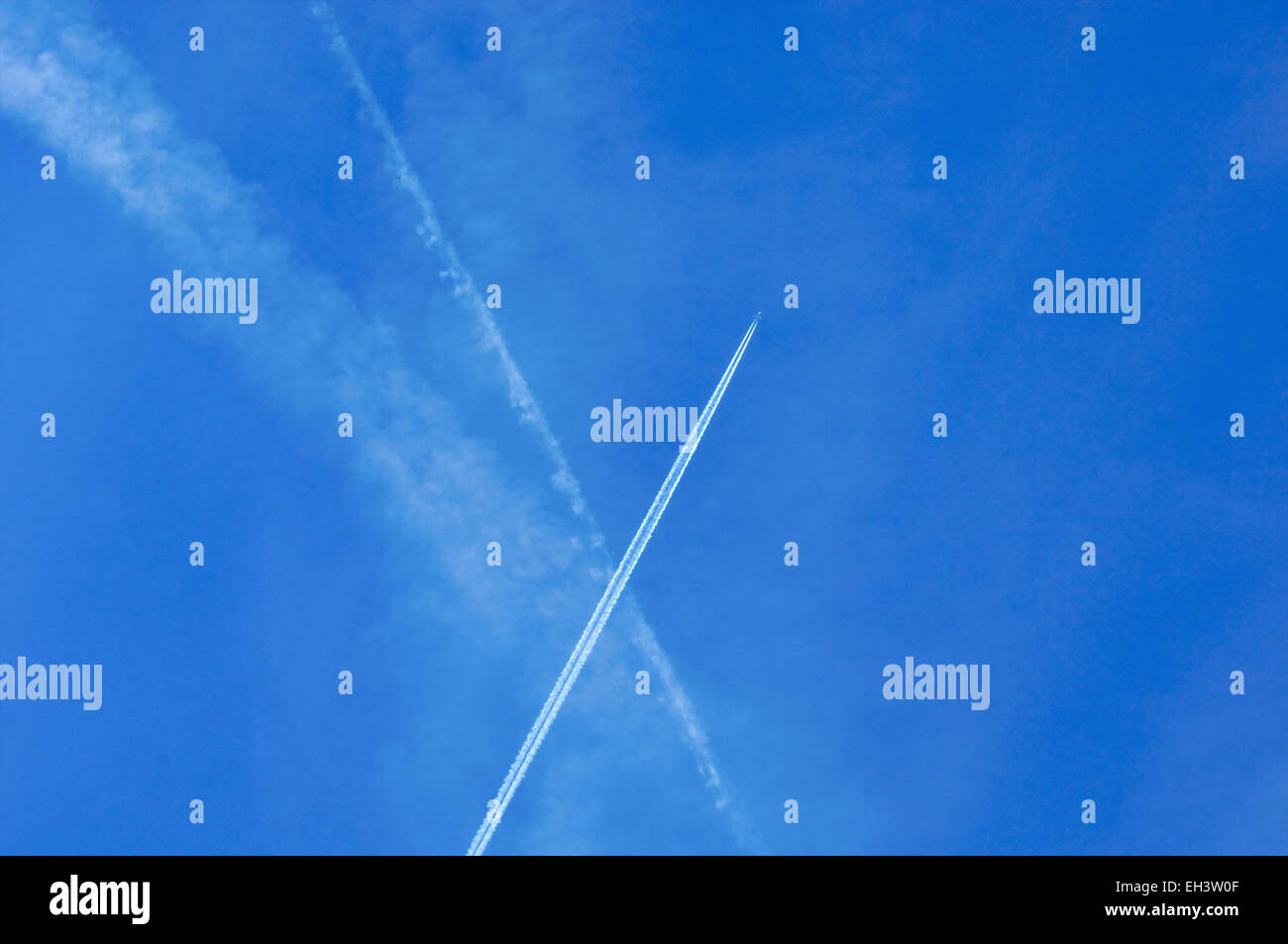 Blauer Himmel mit Chemtrails und Kondensstreifen in der Luft an einem sonnigen Tag Stockfoto