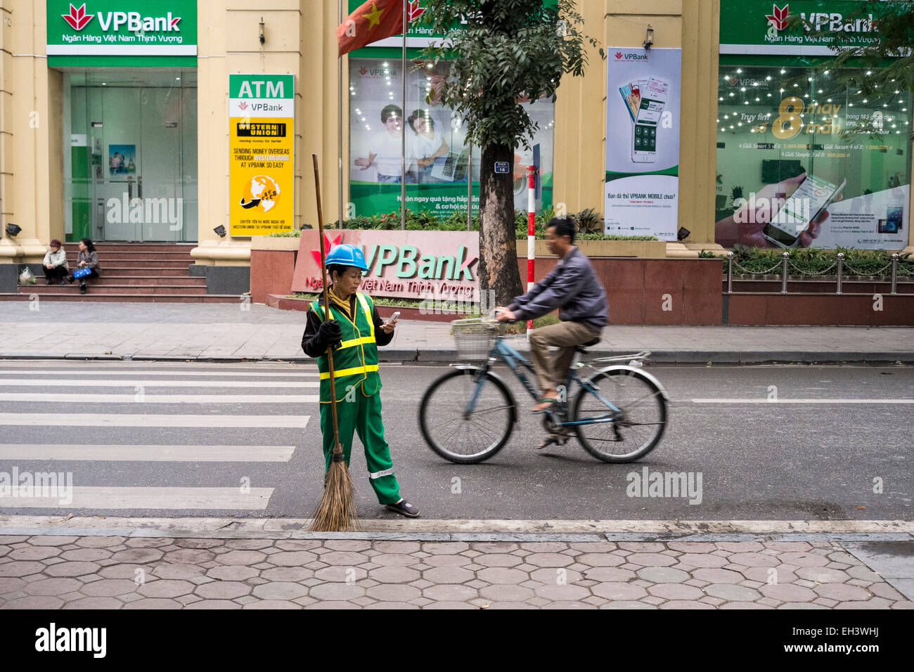 Ein Radfahrer und eine Straße Reiniger in Hanoi, Vietnam Stockfoto
