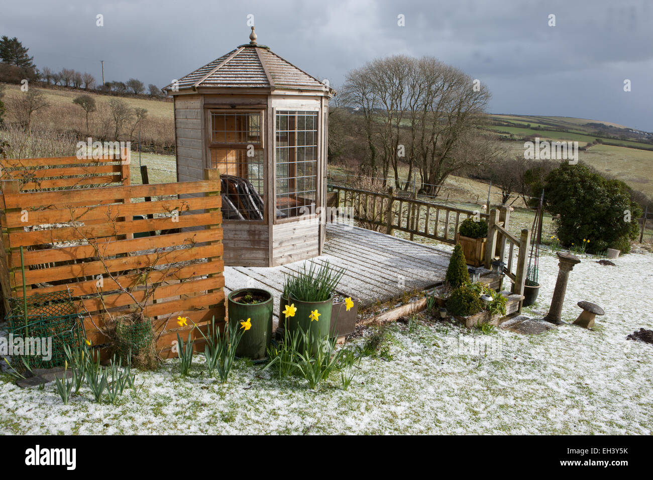 Ungewöhnliche Wetter für März in Cornwall, deckt ein Rückgang von Schnee, der Rasen und der Belag rund um das Gartenhaus. Stockfoto