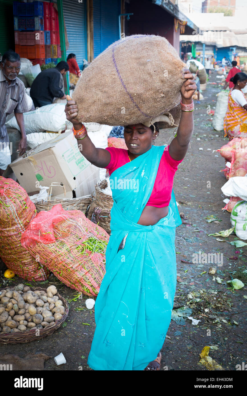 Indische Frau trägt Gemüse in einem Sackleinen-Beutel über den Kopf Stockfoto