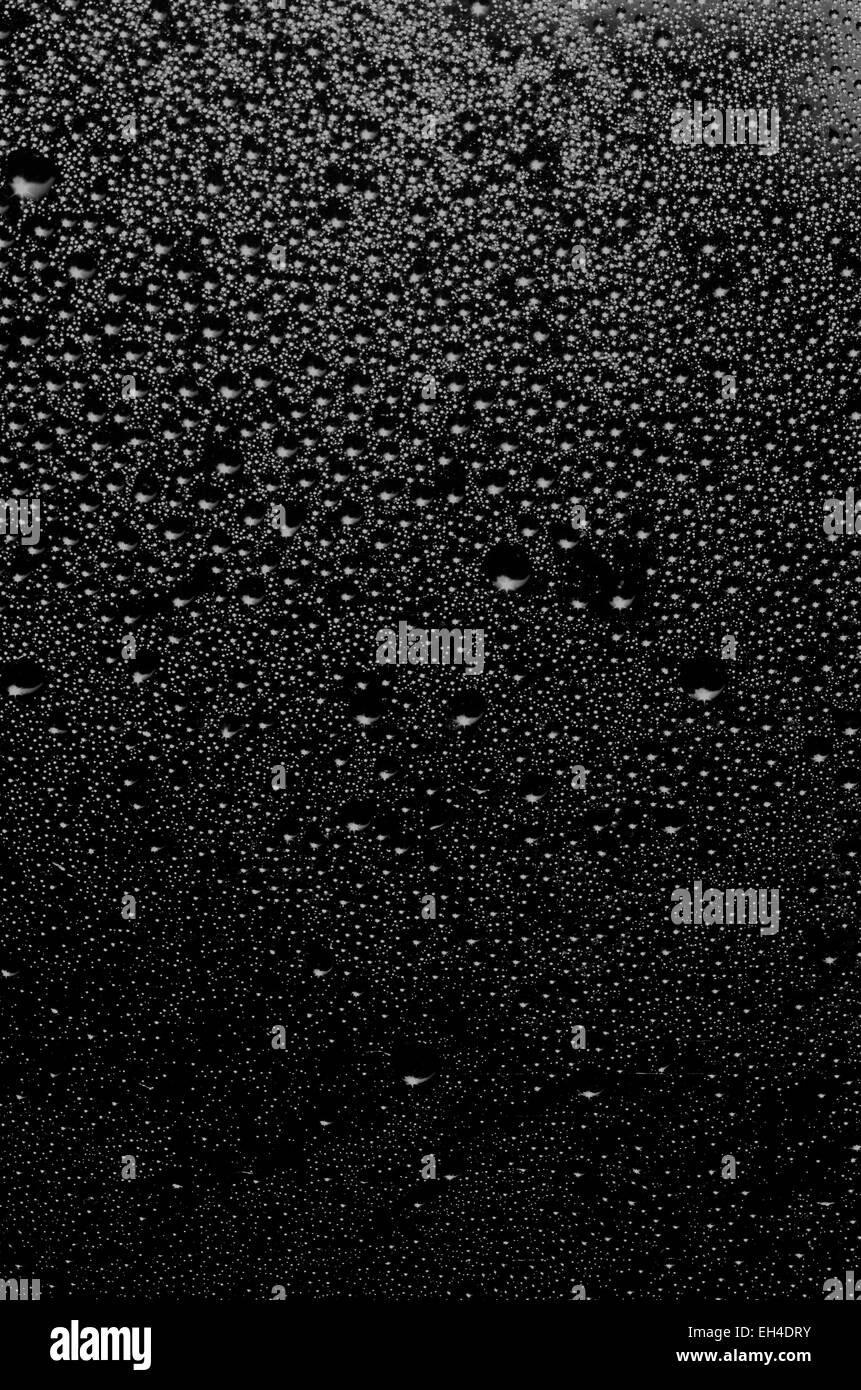 Gruppe von Tropfen mit verschiedenen Dimensionen auf einer Oberfläche in schwarz und weiß als Hintergrund Stockfoto