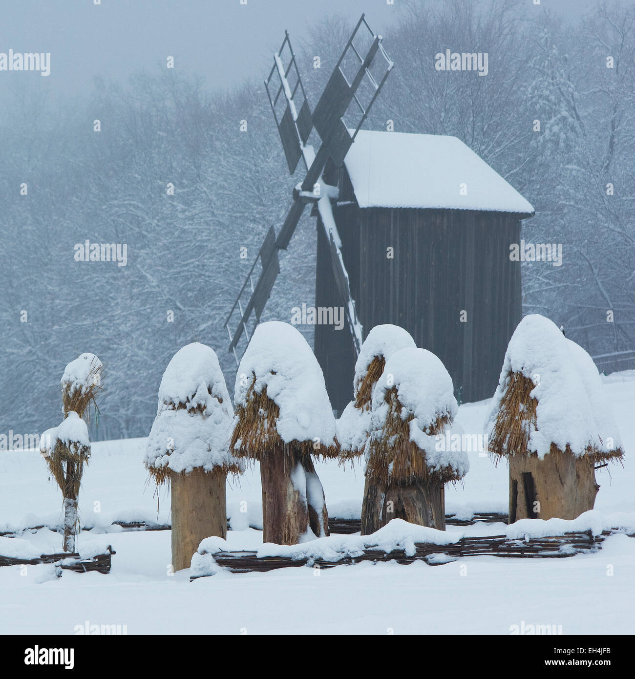 Landschaft mit Mühle aus Holz und Bienenstöcke auf dem Schnee. Ukraine, Kiew, Museum der Holzarchitektur Pirogowo, quadratisch Stockfoto