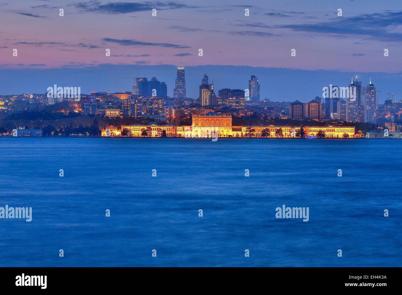 Türkei, Istanbul, Besiktas Bezirk, Dolmabahce Palast (Dolmabahce Sarayi), Nachtansicht von einem beleuchteten Palast vor einem modernen städtischen Bereich am Meer Stockfoto