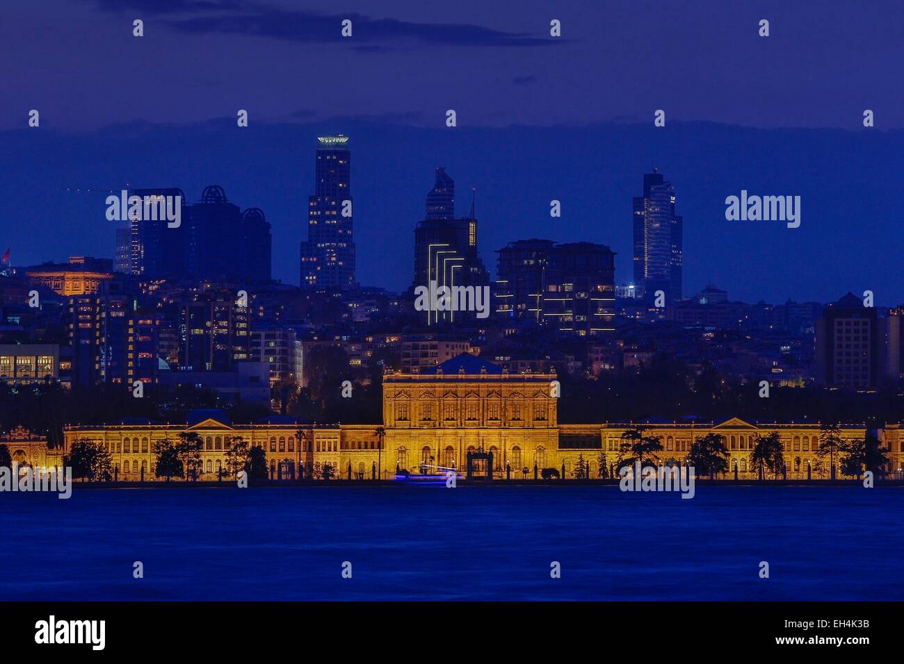 Türkei, Istanbul, Besiktas Bezirk, Dolmabahce Palast (Dolmabahce Sarayi), Nachtansicht von einem beleuchteten Palast vor einem modernen städtischen Bereich am Meer Stockfoto