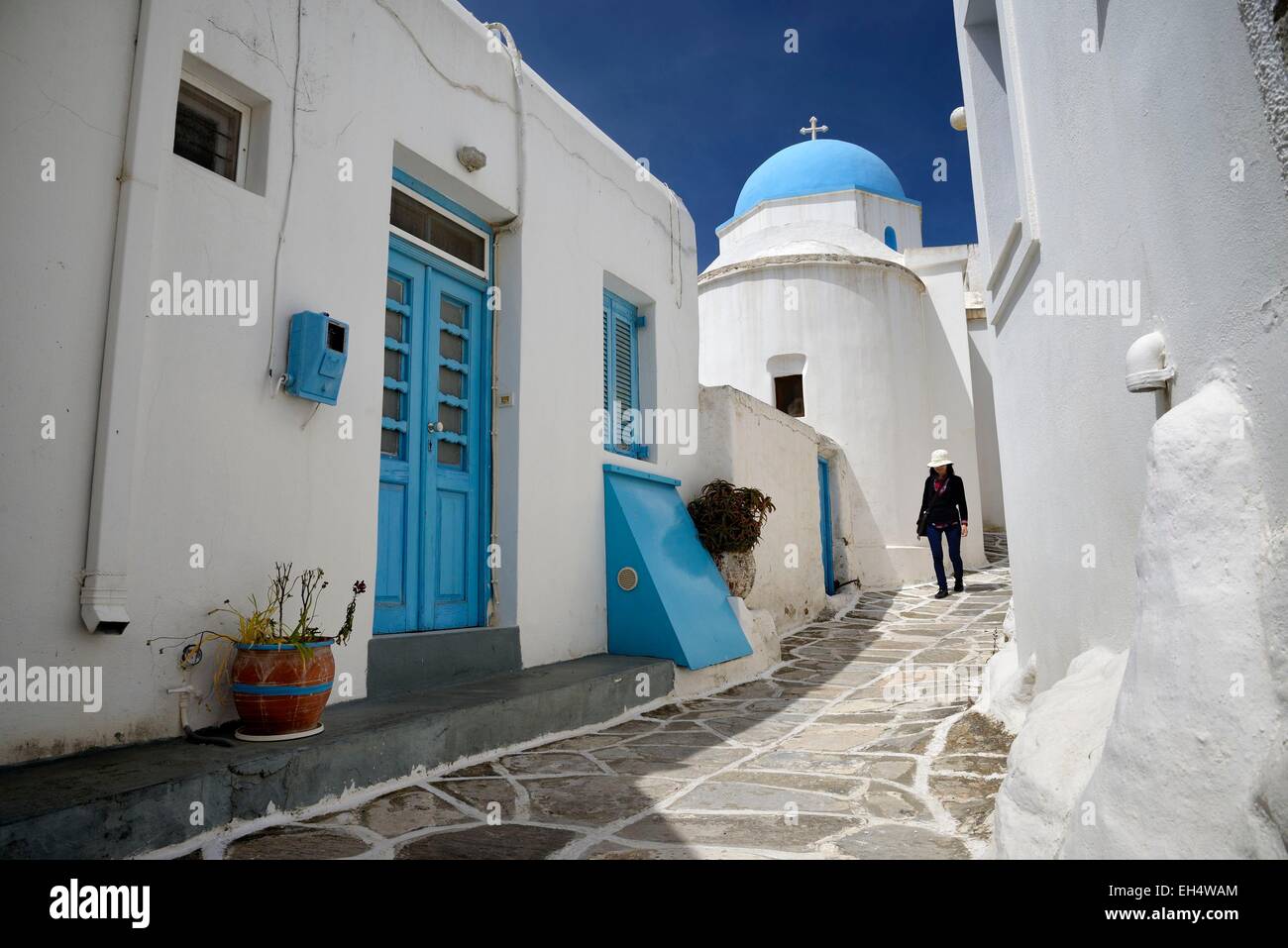 Griechenland, Kykladen, Insel Paros, Frau zu Fuß in einer schmalen Straße im Dorf Lefkes, kleine Kirche mit einem blauen DomeEmirats Arabes Unis Stockfoto