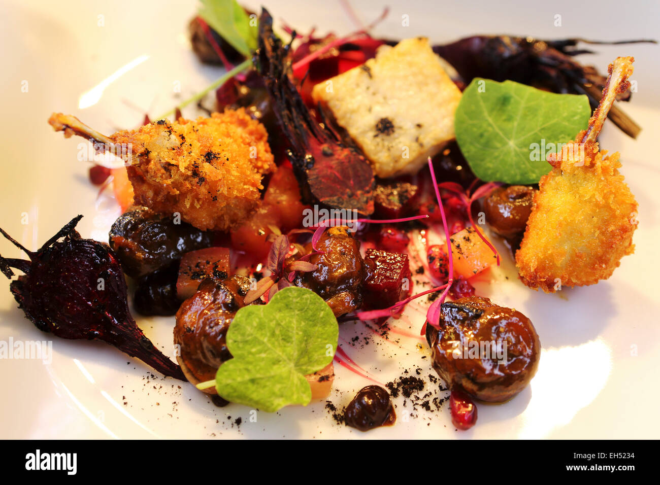 Ein Teller mit gebratener Aylesbury Bauernhof Schnecken, Dorset schwarzen Knoblauch gegrillt Baby rote Beete, Confit Hähnchenschenkel Flügel und Frösche. Stockfoto