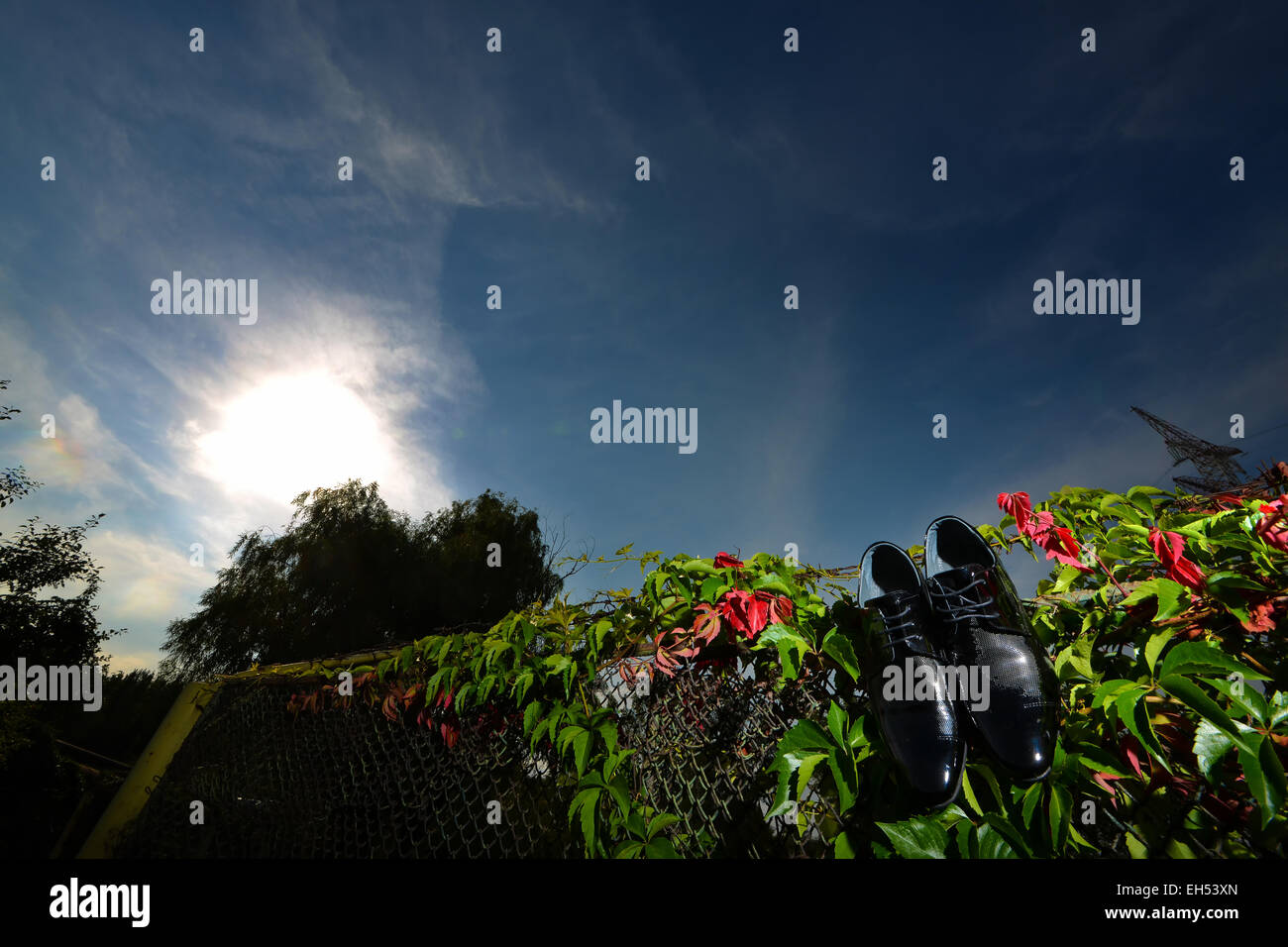 Schwarze Schuhe hängen am Zaun Hintergrund blauer Himmel zu pflegen Stockfoto