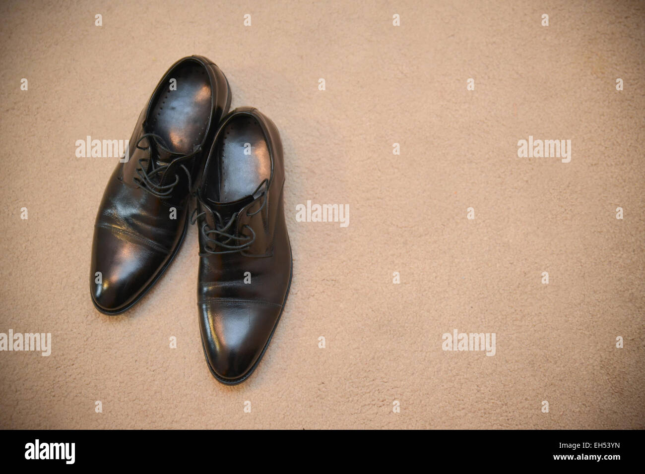 Elegante schwarze Schuhe liegen auf einem braunen Teppich Stockfoto