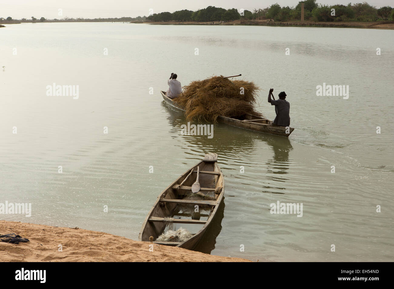 In der Nähe von NIAMEY, NIGER, 15. Mai 2012: Fährmänner Heuballen über den Fluss Niger tragen Stockfoto