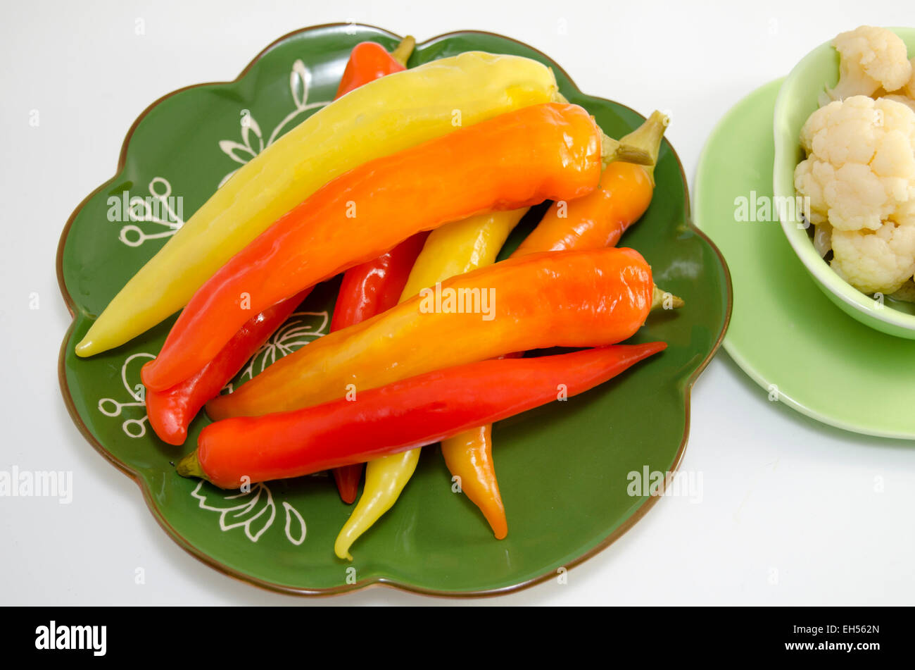 Eingelegte Paprika auf einer grünen Platte isoliert auf weiss Stockfoto