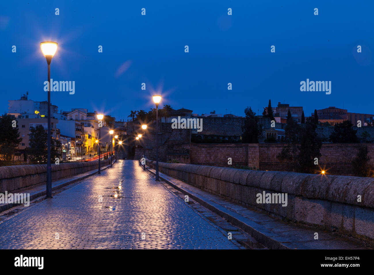 Fuß die alte römische Kopfsteinpflaster Brücke in Merida Spanien spät an einem regnerischen Abend, Straßenlaternen, die nasse Fahrbahn reflektiert Stockfoto