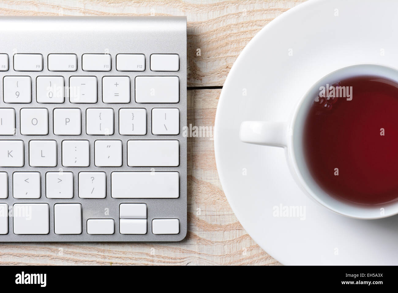 Nahaufnahme einer Computer-Tastatur und Tasse heißen Kaffee auf einem weißen rustikalen Tisch. Hohen Winkel im Querformat gedreht. Stockfoto