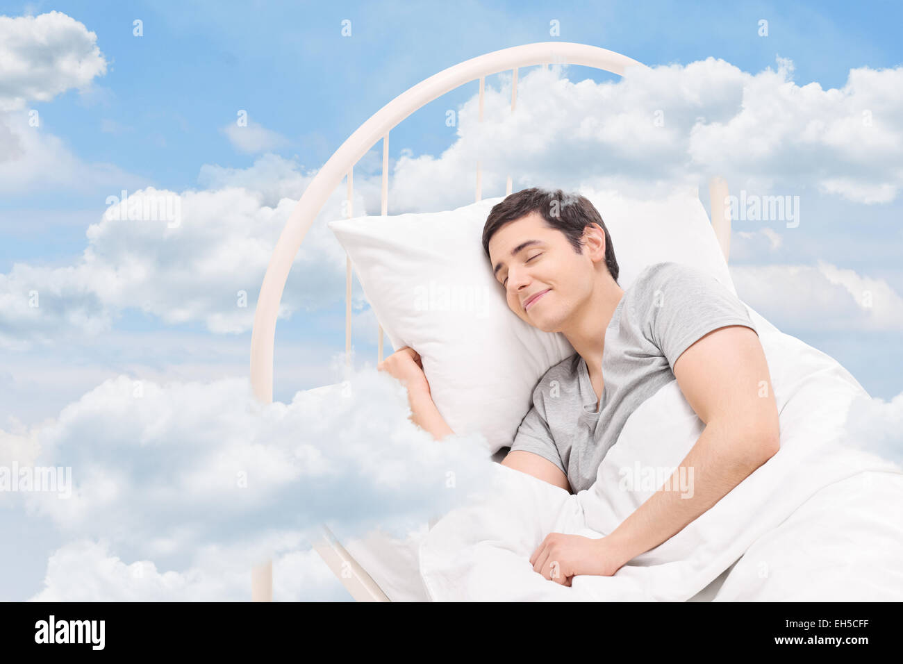 Fröhliche Menschen schlafen auf einem Bett in den Wolken Stockfoto