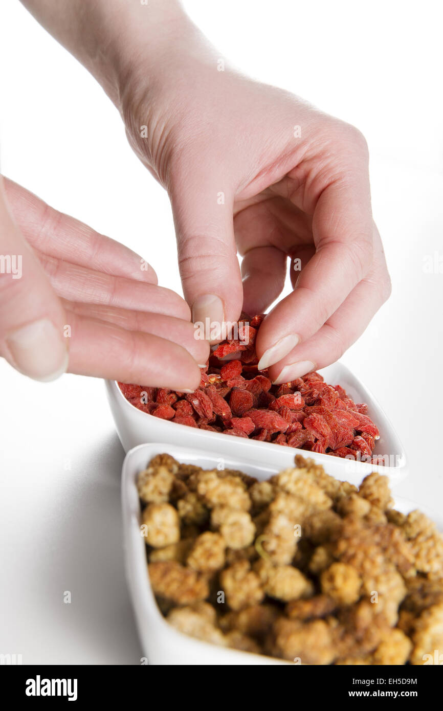 Frau Essen und essen Goji-Beere / Wolfsbeere und Maulbeere aus einer Schüssel auf weißem Hintergrund. Stockfoto