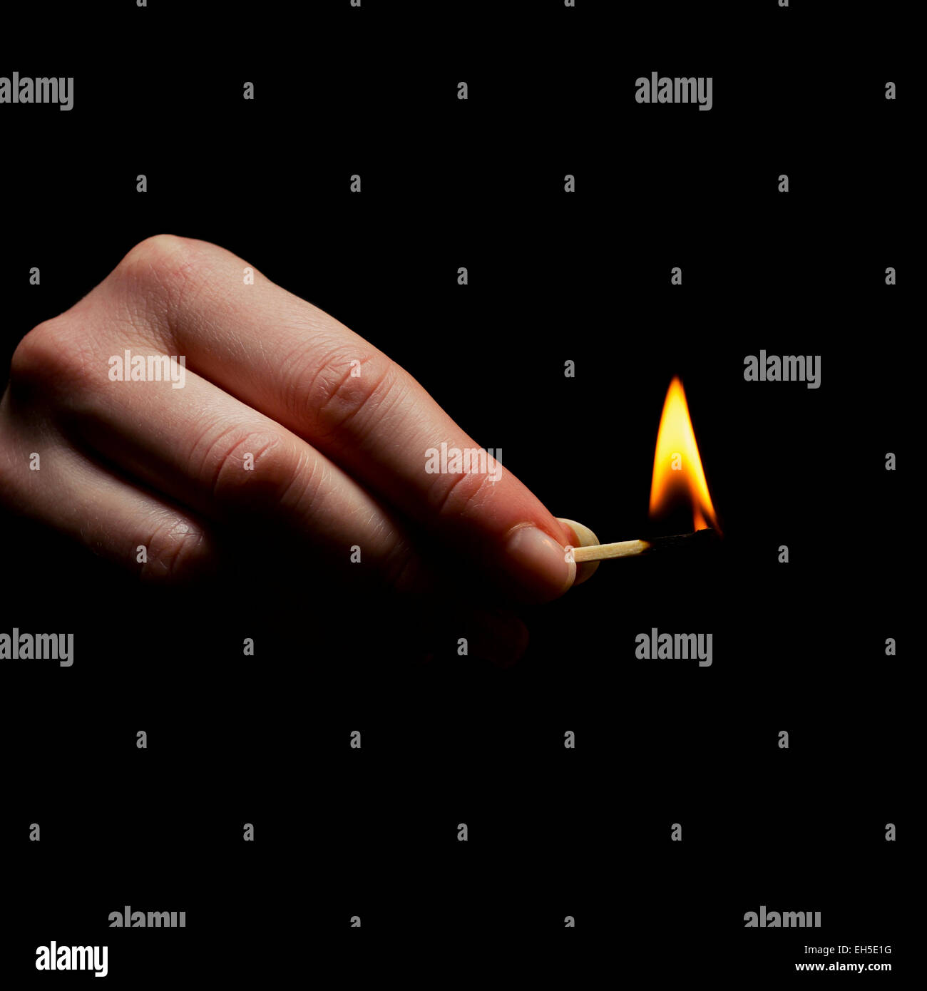 Frau hält ein Match / Matchstick in Brand. Ein Licht im Dunkeln. Stockfoto