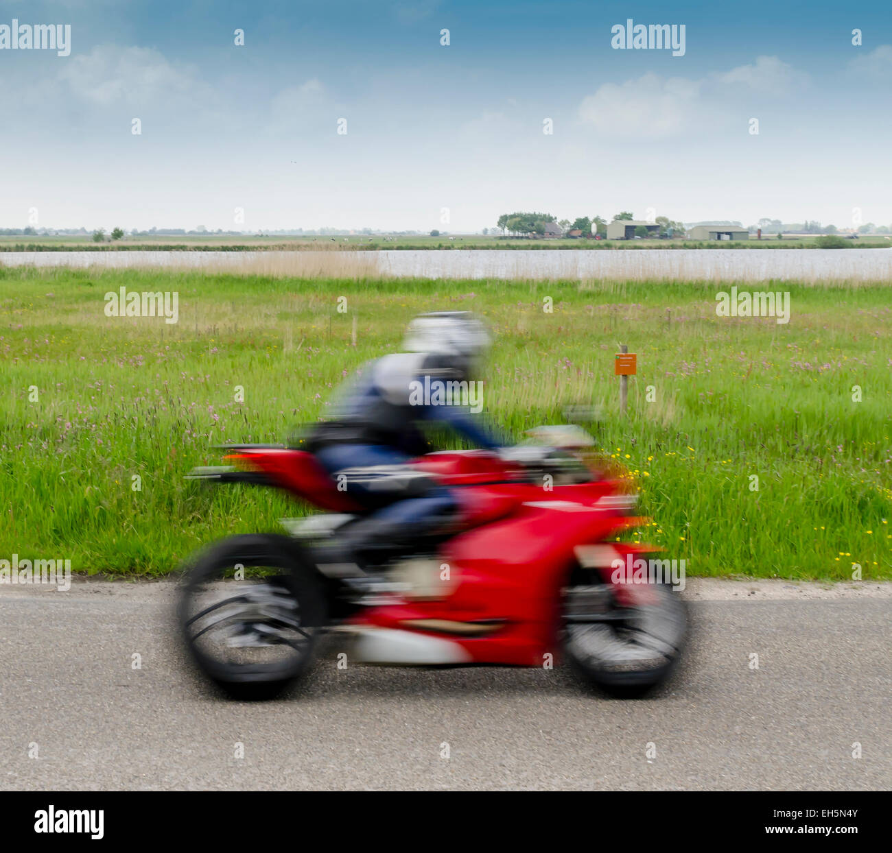 Schnelle Motorradfahrer auf dem roten Motorrad in der Nähe von e-Naturschutzgebiet von Staatsbosbeheer. Stockfoto