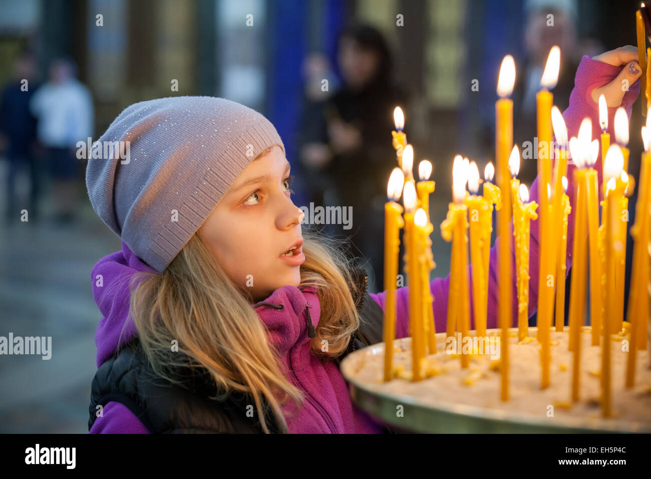 Blonde kaukasische Mädchen mit Kerzen in der russischen orthodoxen Kirche Stockfoto