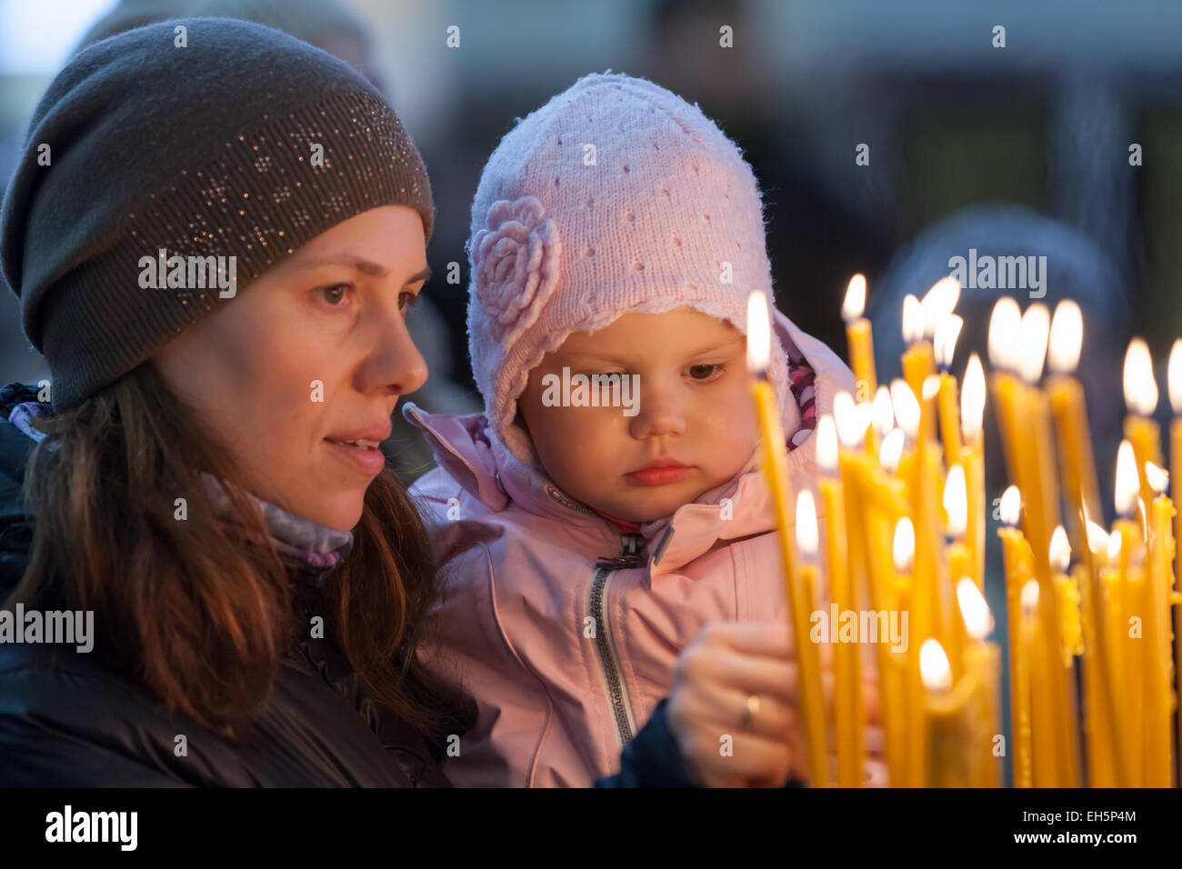 Mutter und ihre kleine blonde kaukasische Mädchen mit Kerzen in der russischen orthodoxen Kirche Stockfoto