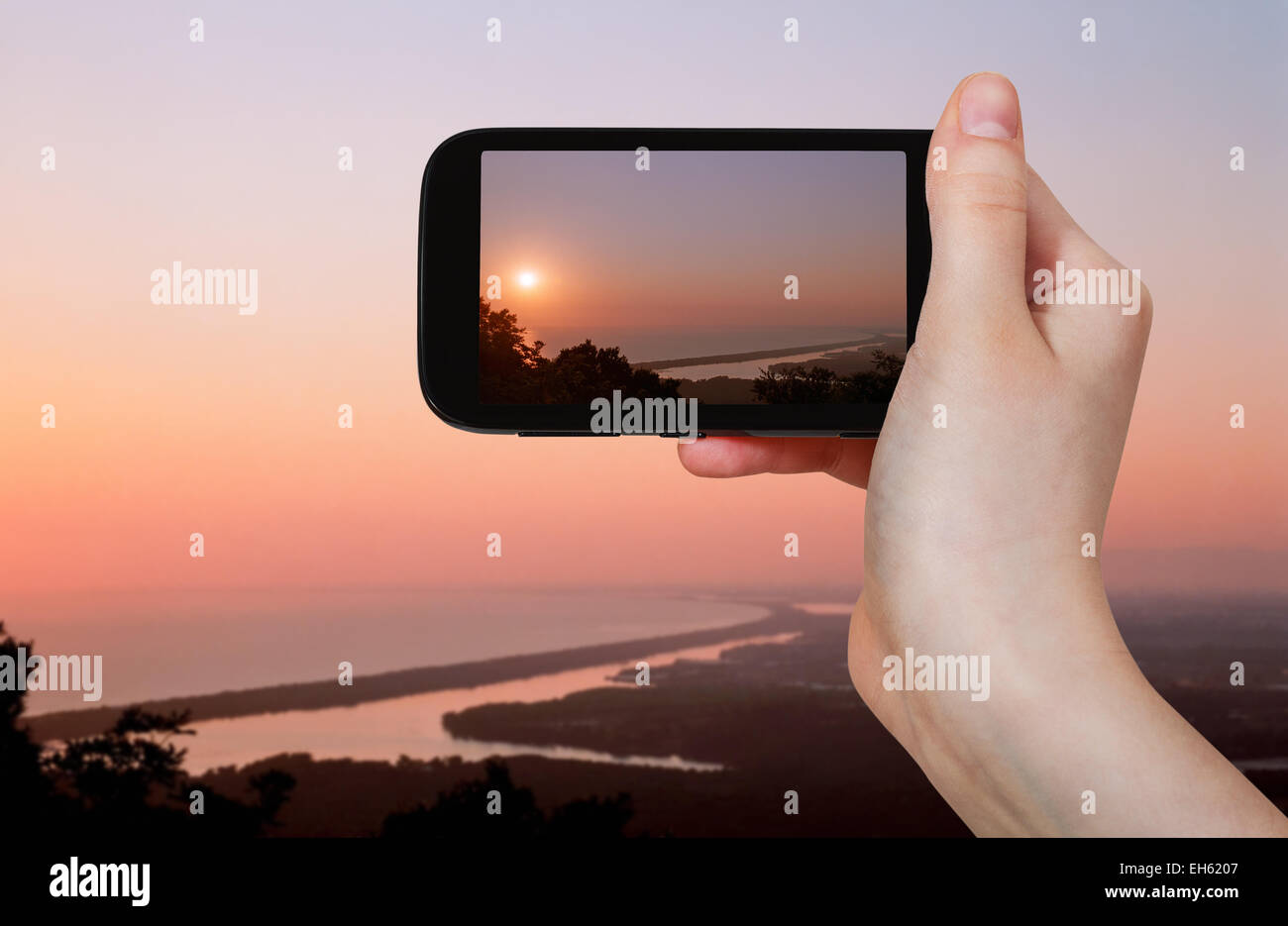 Reisen Sie Konzept - Touristen nehmen Foto von Salzseen bei Rosa Sonnenuntergang in der Nähe von Sabaudia Stadt auf mobile Gadget, Italien Stockfoto