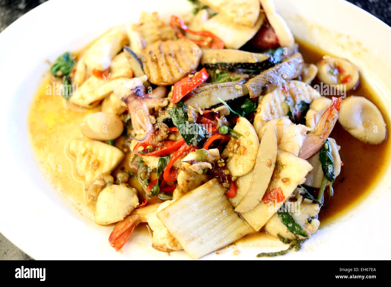 Rühren Sie gemischte frittierte Meeresfrüchte auf einem weißen Teller in einem Restaurant. Stockfoto