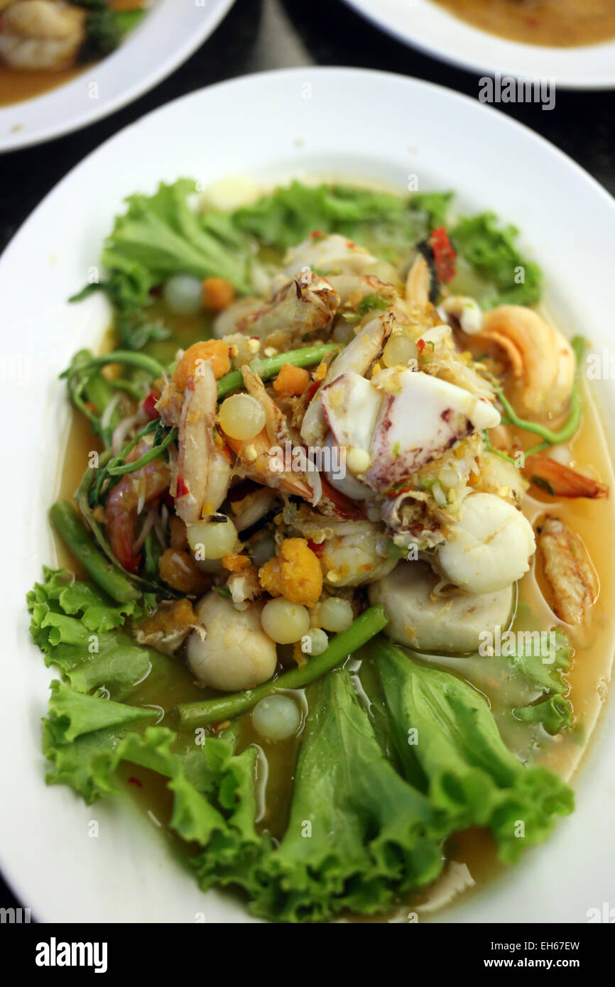 Rühren Sie gemischte frittierte Meeresfrüchte auf einem weißen Teller in einem Restaurant. Stockfoto