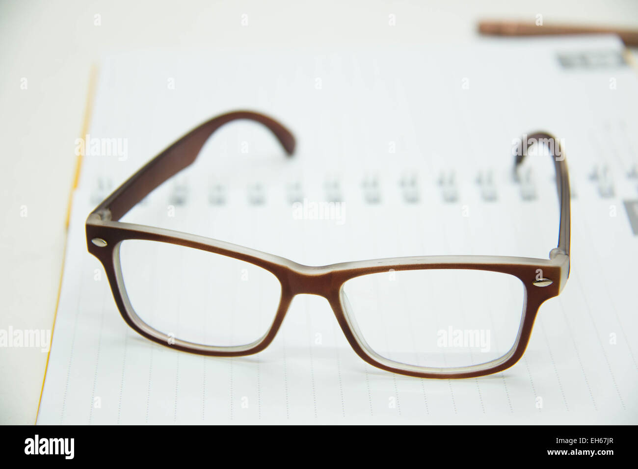 Schreibstift bereit zum Erstellen von Notizen auf einem Notebook offene Papierbrille über weiß. Stockfoto