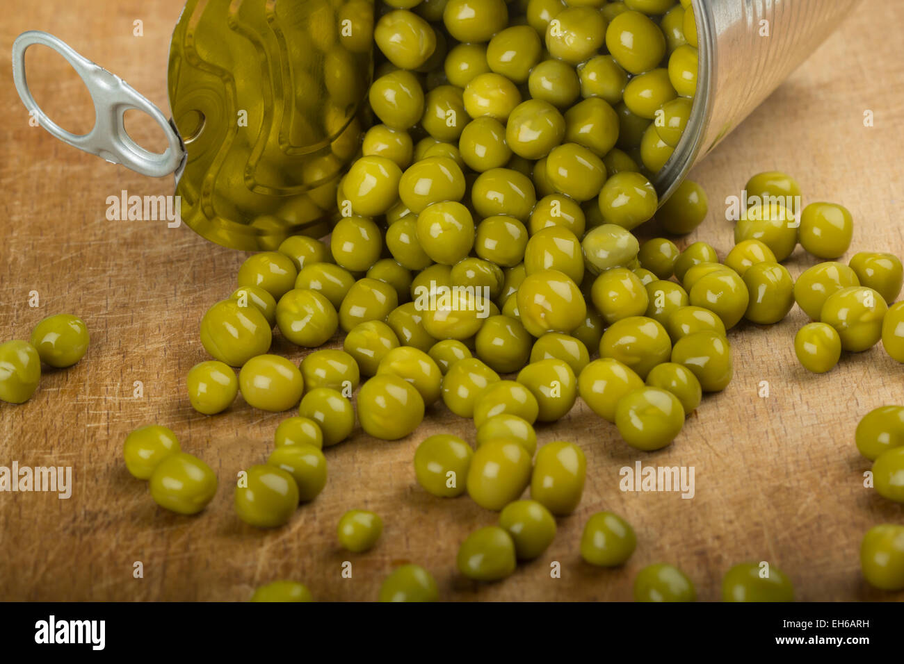 Grüne Erbsen aus einer Blechdose übergreifen Holz Hintergrund Stockfoto