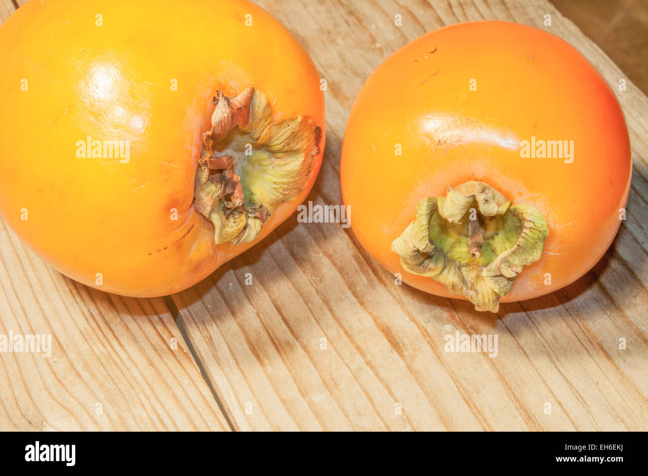 Zwei orangefarbene Kaki-Frucht, auf hölzernen Hintergrund Stockfoto