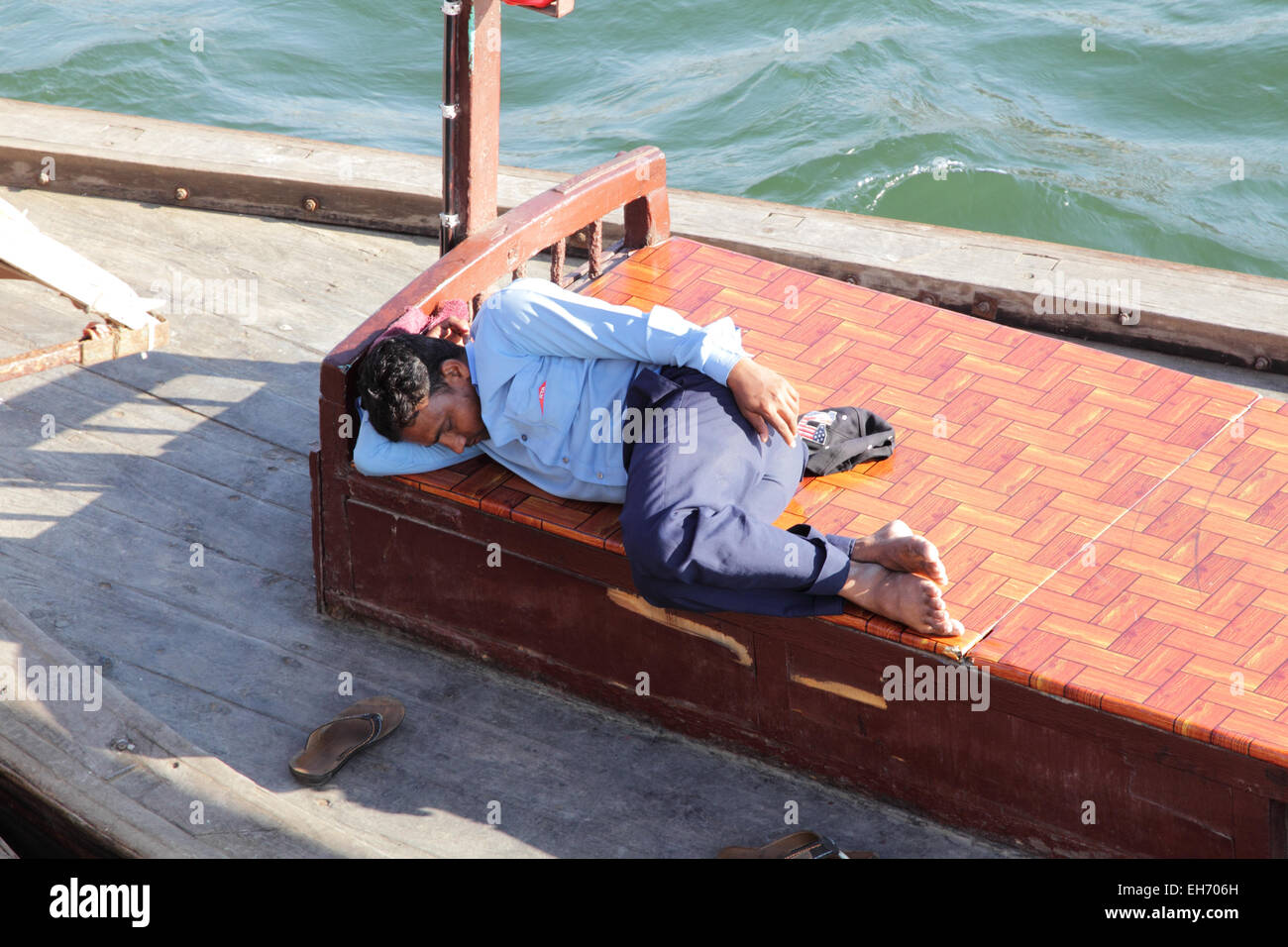Mann schläft auf einem Abra, eine typische Fähre auf dem Dubai Creek in Dubai, Vereinigte Arabische Emirate. Stockfoto