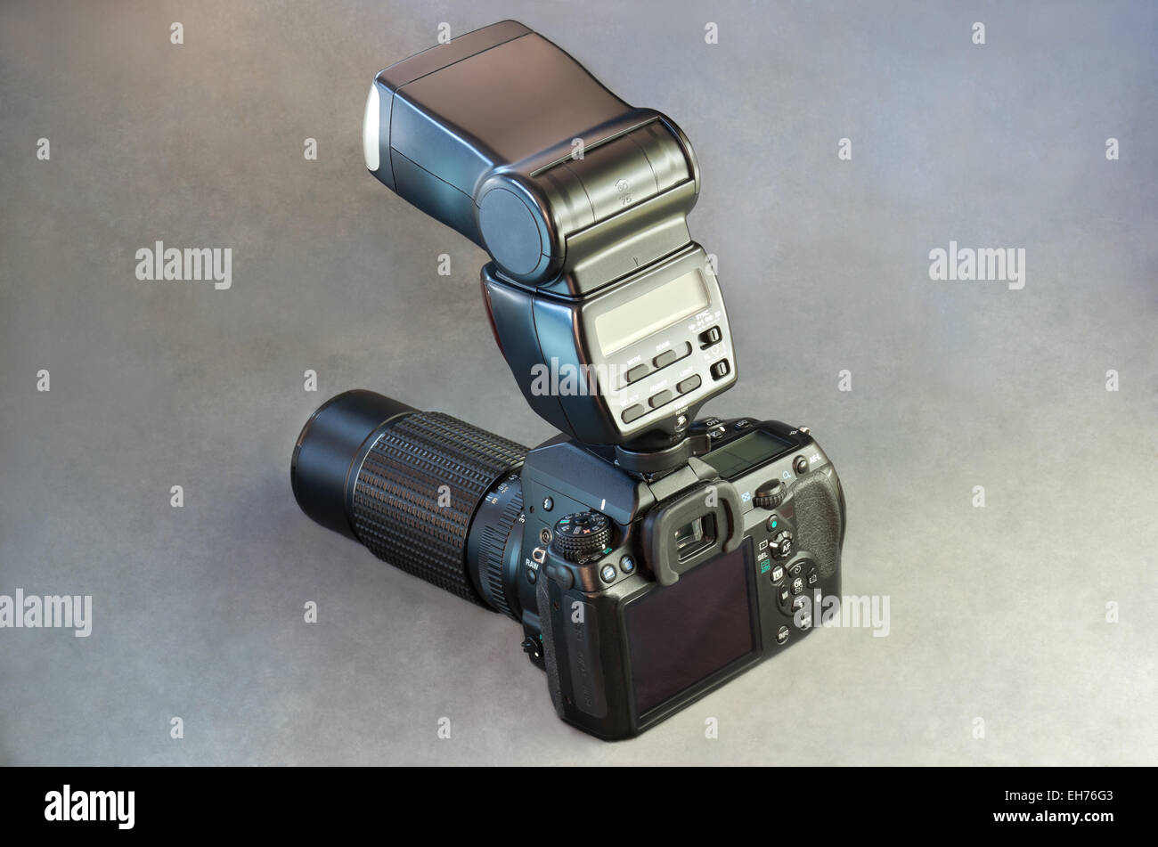 Digitale Spiegelreflexkamera mit Blitzgerät und Teleobjektiv auf grauem Hintergrund Stockfoto