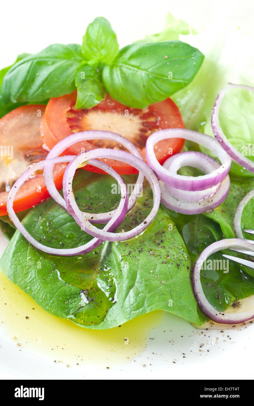 Salat mit spanische Zwiebeln und rote Tomaten. Mit Olivenöl und Pfeffer serviert. Stockfoto